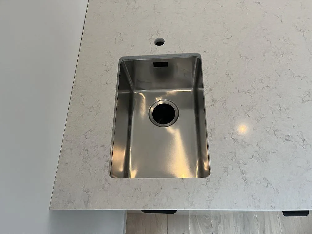 Underlimmad rostfri diskho med separat blandarhål i en köksö av Silestone Snowy Ibiza i ett kök i Hönö.
