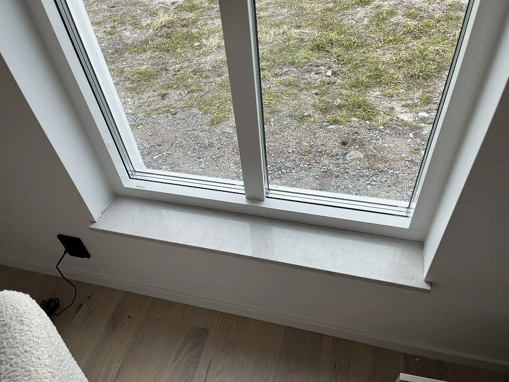 Fönsterbänk i Silestone Snowy Ibiza, vit kvartskomposit, vid ett fönster i ett kök i Hönö.