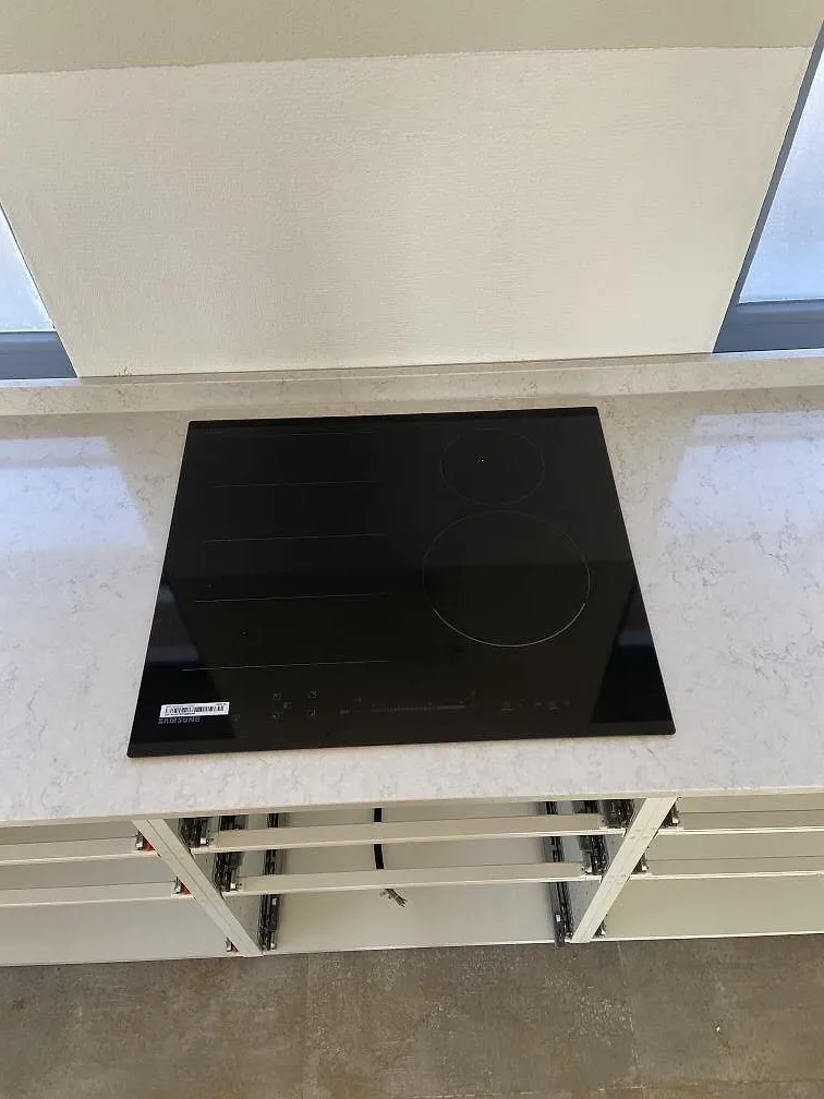 Induktionshäll nedfälld i en halvö av vit Silestone Snowy Ibiza i ett kök i Höör.