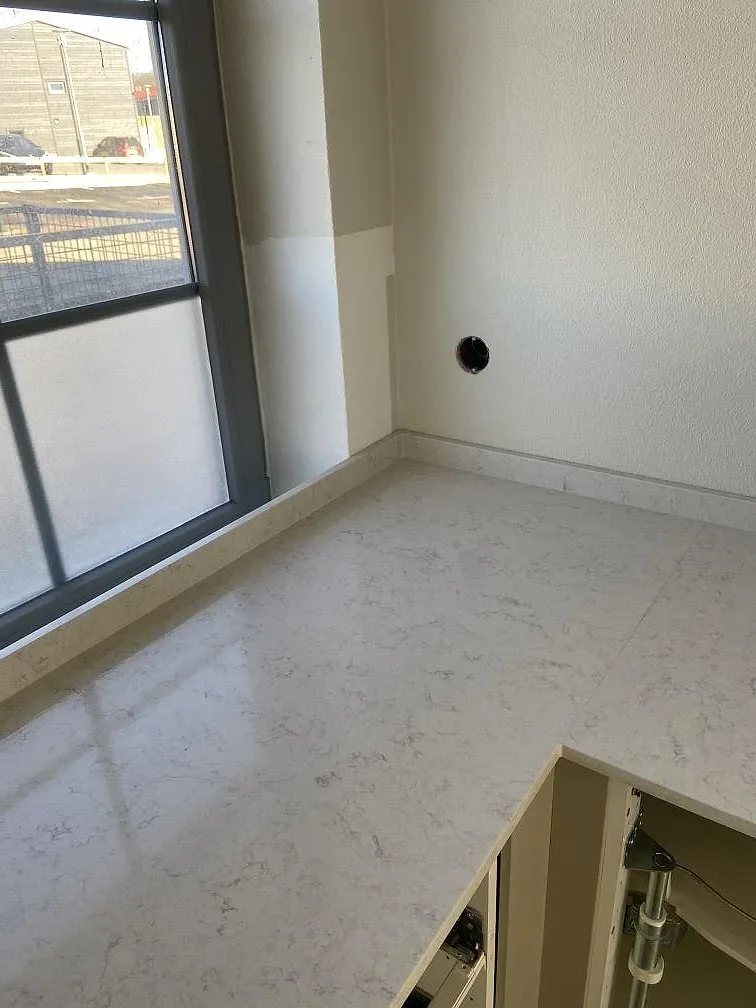Fönsterbänk och stänkskydd i vit Silestone Snowy Ibiza med grå ådring vid köksfönstret i Höör.