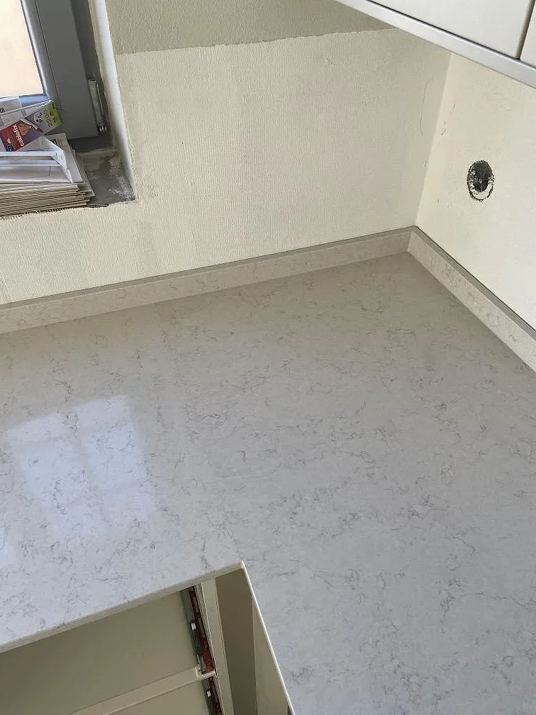 Stänkskydd i vit kvartskomposit Silestone Snowy Ibiza monterat mot vägg i ett kök under montering i Höör.