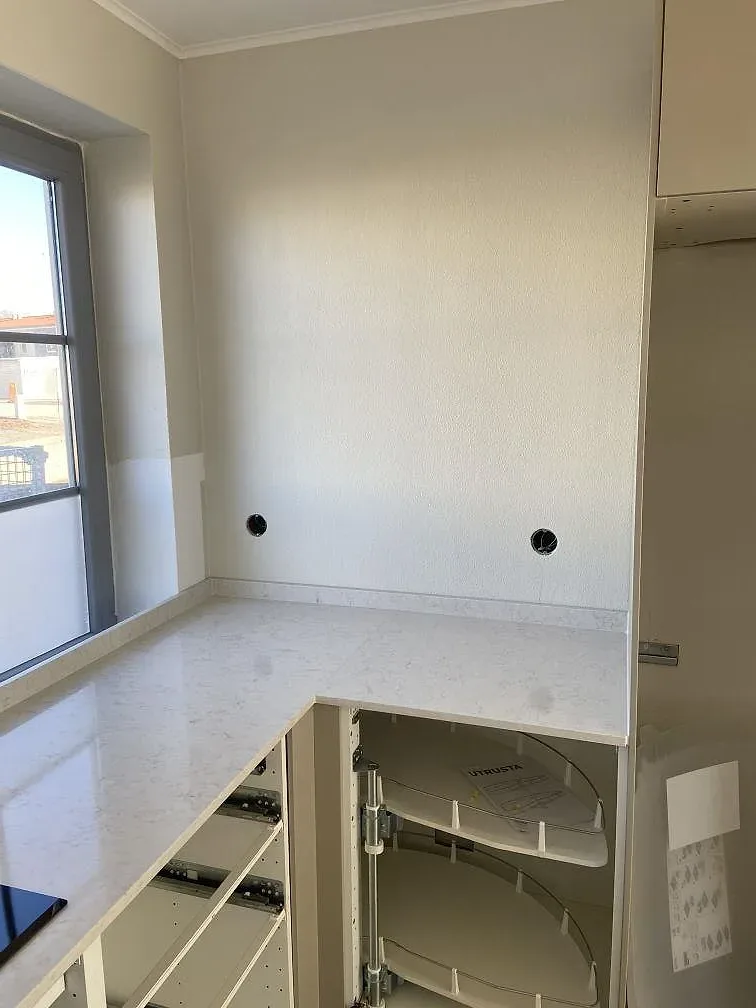Stänkskydd i vit Silestone Snowy Ibiza med borrade blandarhål ovanför diskbänken i ett kök i Höör.