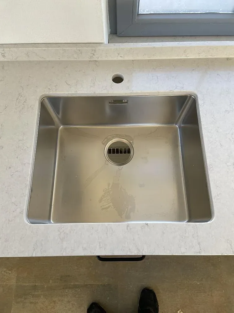 Underlimmad rostfri diskho med separat borrat blandarhål i en bänkskiva av vit Silestone Snowy Ibiza i Höör.