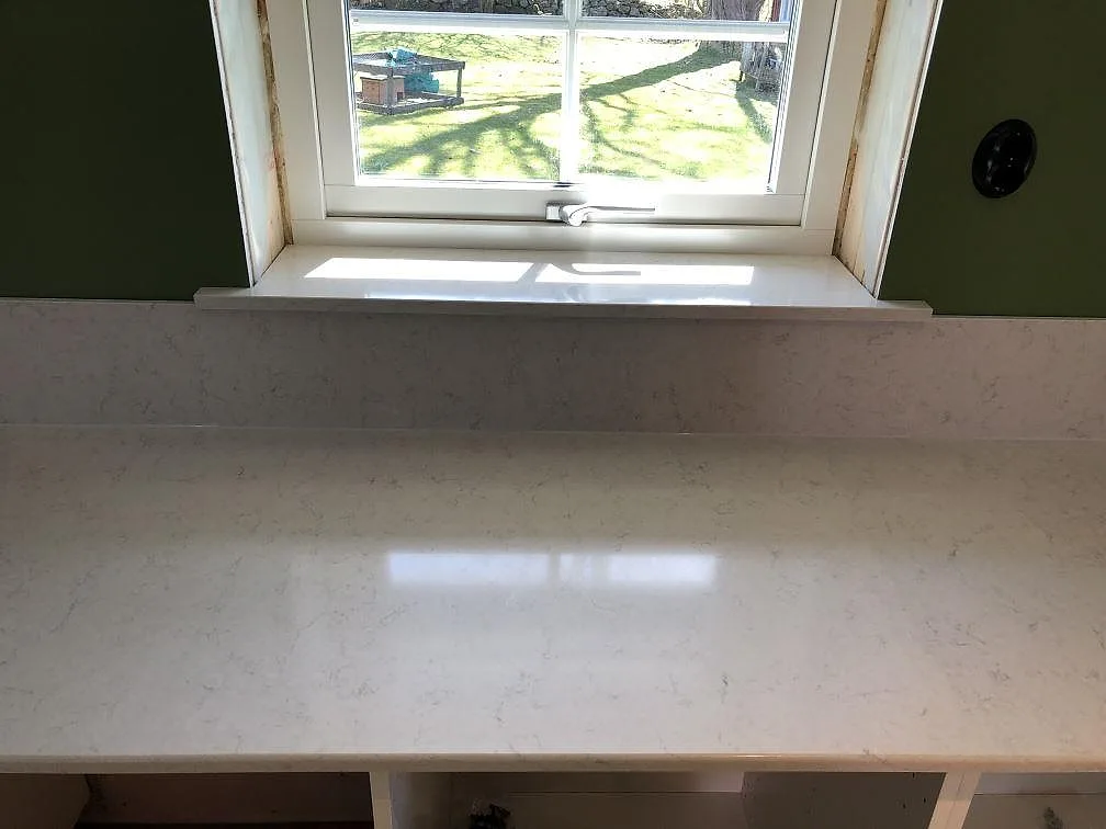 Köksbänkskiva i vit Silestone Snowy Ibiza med underlimmad rostfri diskho och borrat blandarhål i ett kök i Hörby.
