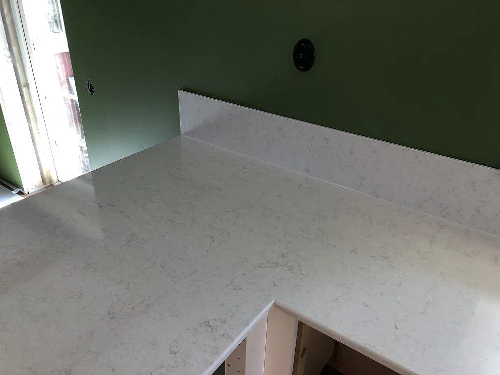 Polerad köksbänkskiva och fönsterbänk i vit Silestone Snowy Ibiza med diskret grå ådring i ett kök i Hörby.