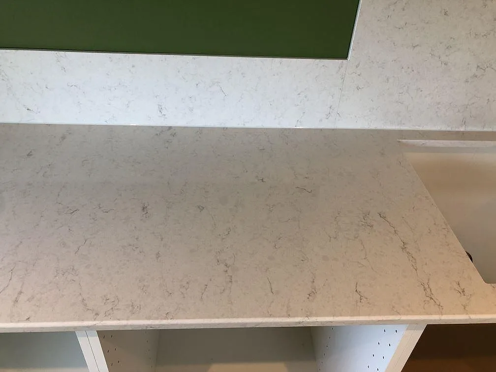 Top-down på polerad köksbänkskiva i vit Silestone Snowy Ibiza med uppvikt stänkkant i ett kök i Hörby.