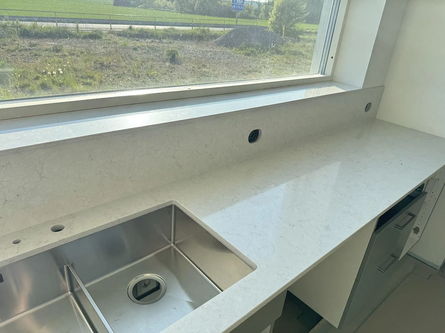 Köksbänkskiva i polerad Silestone Snowy Ibiza med rostfri diskho, låg stänkkant och fönsterbänk i Holm.