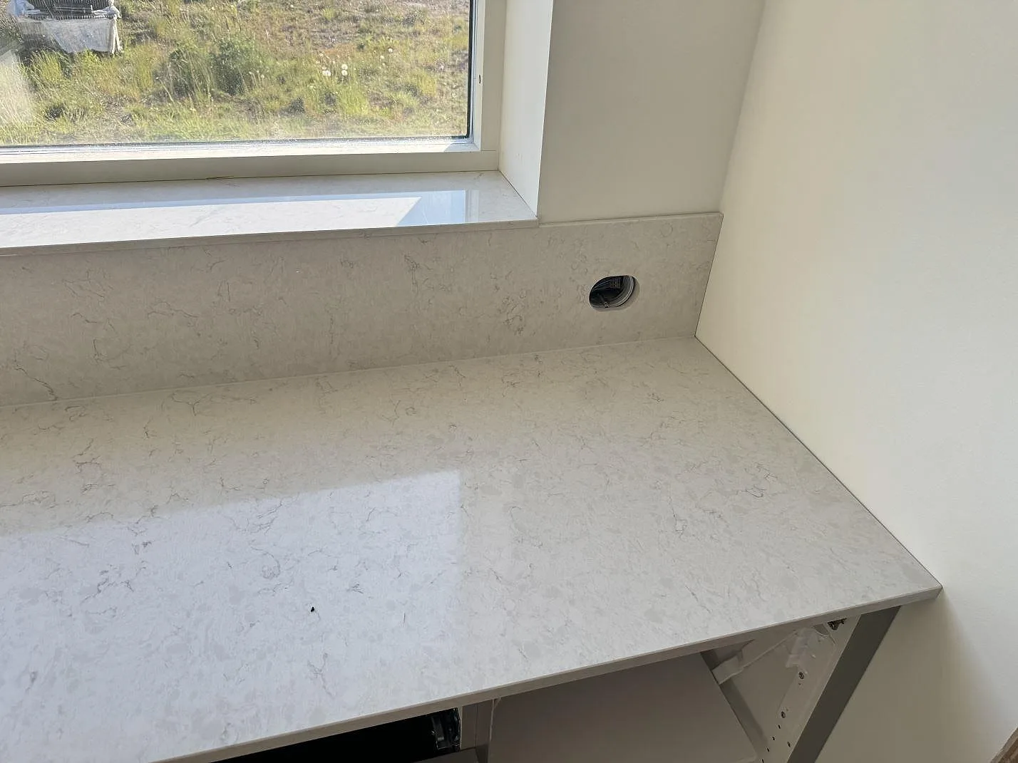 Polerad Silestone Snowy Ibiza som köksö och väggbänk i ett ljusstarkt kök i Holm, med monteringsarbete pågående.