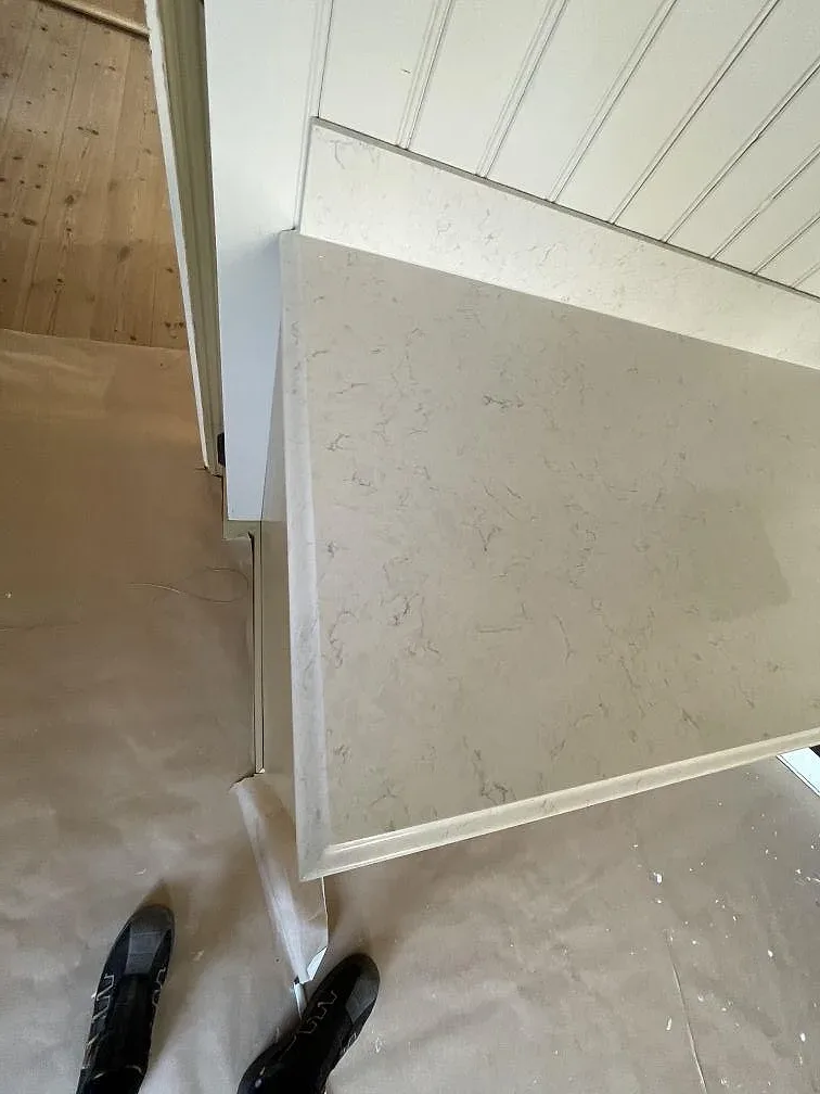 Hornpartiet av en polerad koksbankskiva i vit Silestone Snowy Ibiza med synlig kantprofil och stankskydd i trapanel i ett kok i Hudiksvall.