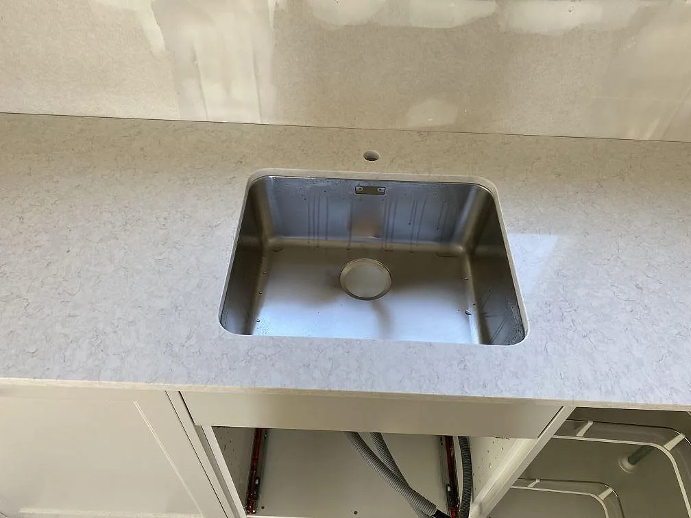 Närbild på diskhozonen i en polerad Silestone Snowy Ibiza köksbänkskiva med ljus ådring i Hunnebostrand.