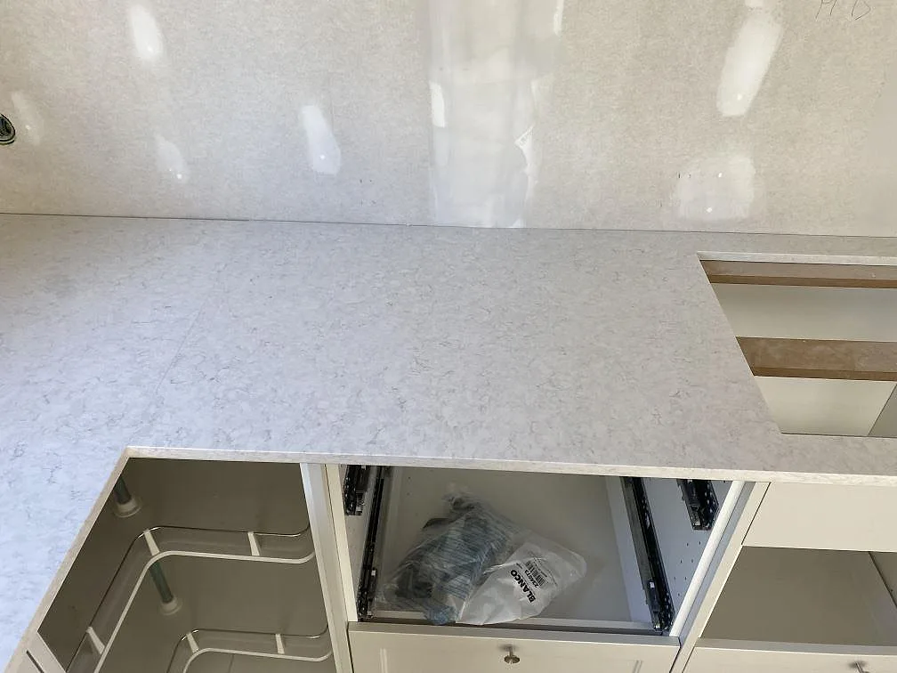 Yta i polerad Silestone Snowy Ibiza mellan diskho och hällöppning i ett vitt kök under montering i Hunnebostrand.