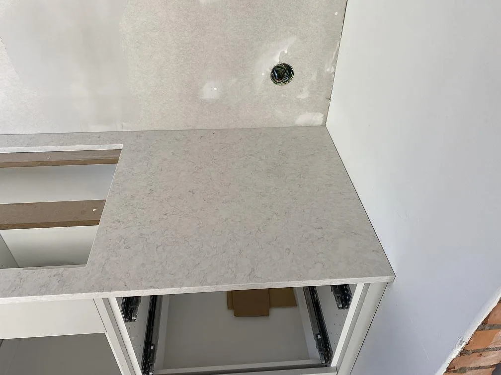 Höger bänkskivedel i polerad Silestone Snowy Ibiza med hällöppning och öppna köksstommar i Hunnebostrand.