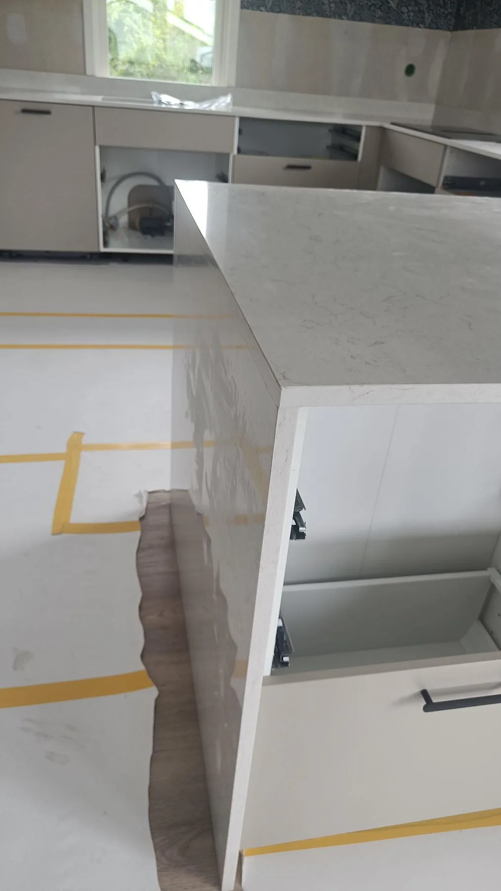 Kant och vattenfallsida på köksö i polerad Silestone Snowy Ibiza under montering i Huskvarna.
