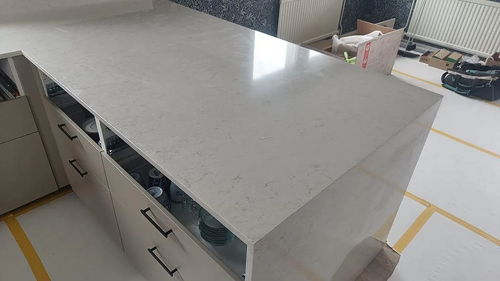 Köksö i polerad Silestone Snowy Ibiza med ljus ådring, vit inredning och monteringsmaterial i rummet i Huskvarna.