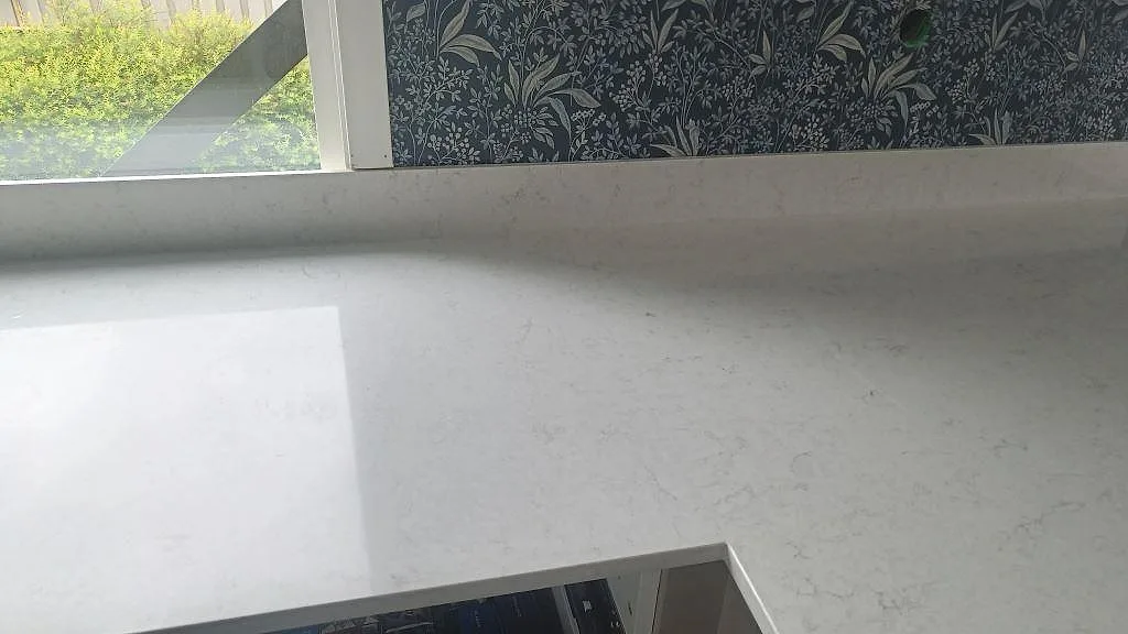 Polerad Silestone Snowy Ibiza på köksbänk vid fönster med låg stenkant och ljus ådring i Huskvarna.