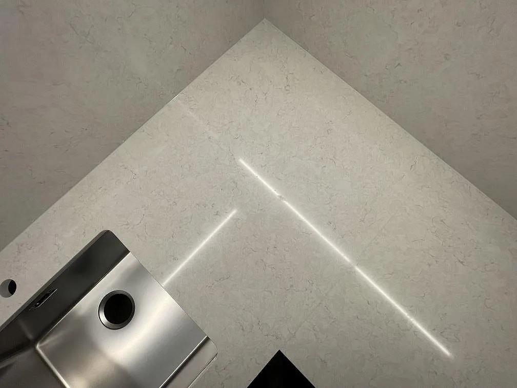 Hörnskarv i polerad köksbänkskiva i Silestone Snowy Ibiza intill den underlimmade rostfria diskhon i ett kök i Järfälla.
