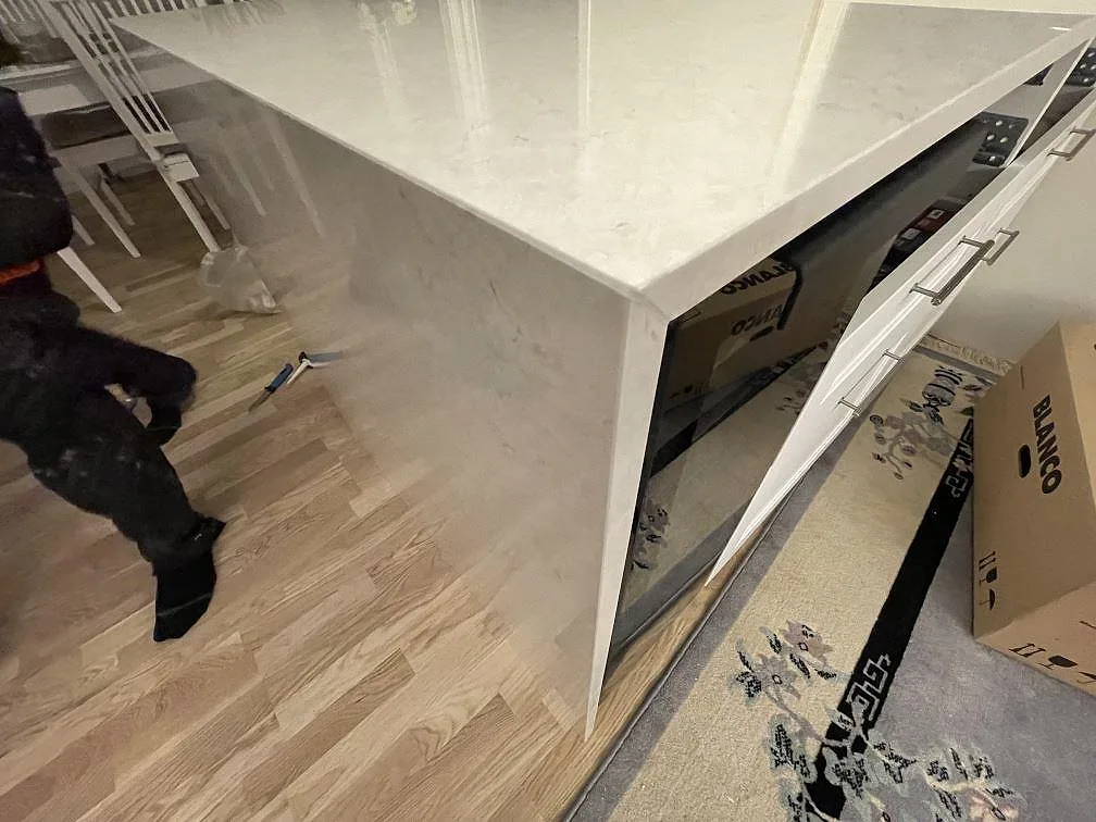 Fristående köksö med polerad helkantssida i Silestone Snowy Ibiza under montering i ett kök i Järfälla.
