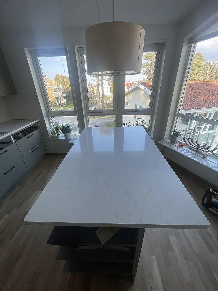 Köksbänkskiva och köksö i vit Silestone Snowy Ibiza, polerad, vid fönster med ljusinsläpp i ett kök i Jönköping.