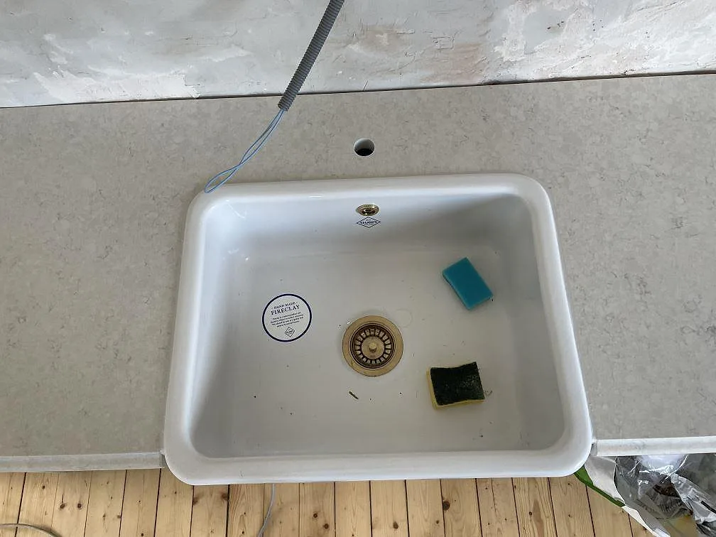 Detalj av vit diskho och blandarhål i en polerad Silestone Snowy Ibiza köksbänkskiva i Kågeröd.