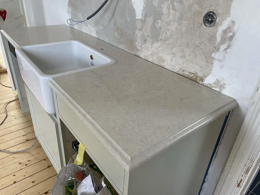 Sidovy av polerad Silestone Snowy Ibiza med vit diskho, avrundad framkant och vägg under renovering i Kågeröd.