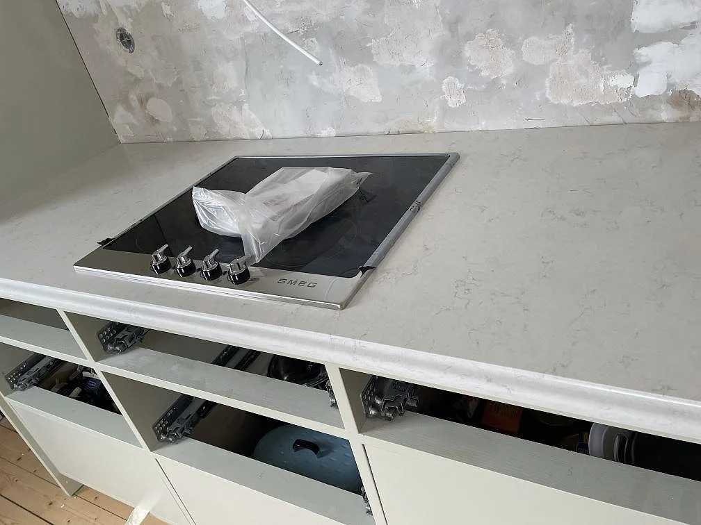 Närbild på svart häll infälld i polerad Silestone Snowy Ibiza med ljus ådring i köket i Kågeröd.