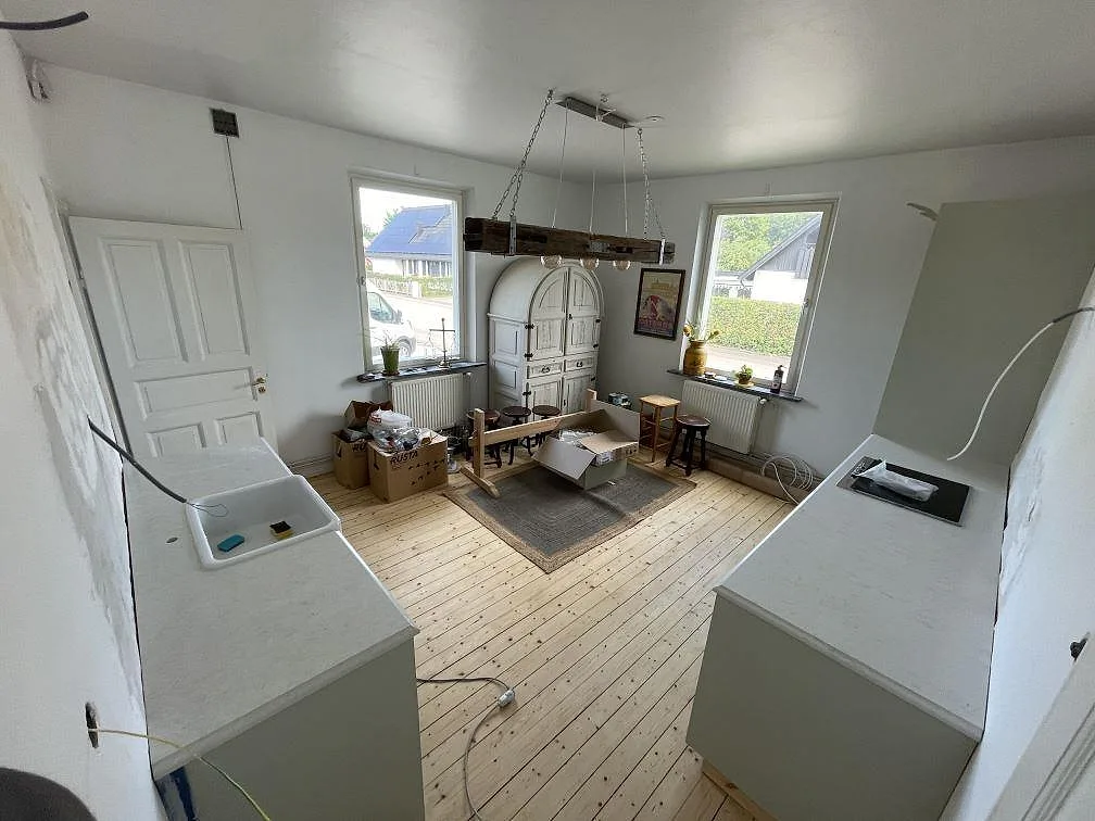 Köksbänkskiva i polerad Silestone Snowy Ibiza med ljus komposityta, vit diskho och svart häll i ett kök under montering i Kågeröd.