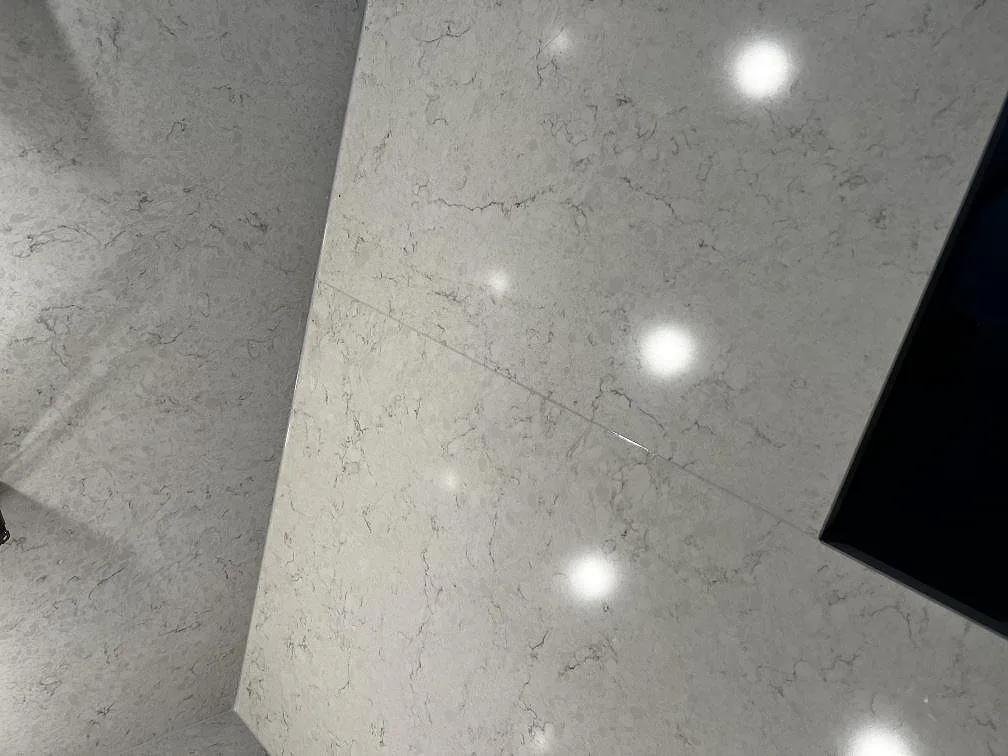 Detalj av polerad Silestone Snowy Ibiza med grå ådring, blank ljusreflex och utsnitt vid hällen i ett kök i Kalmar.