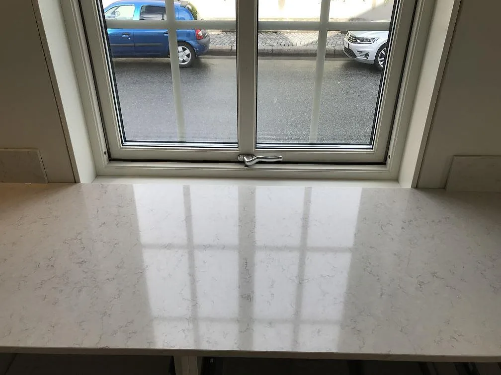 Polerad fönsterbänk i vit Silestone Snowy Ibiza som speglar fönsterspröjsen i ett kök i Karlshamn.