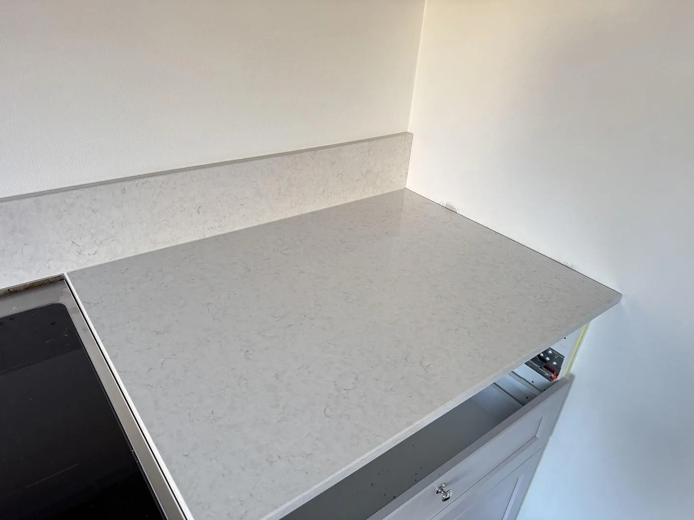 Arbetsyta i polerad Silestone Snowy Ibiza bredvid spisen med matchande stänkkant i ett kök i Karlshamn.