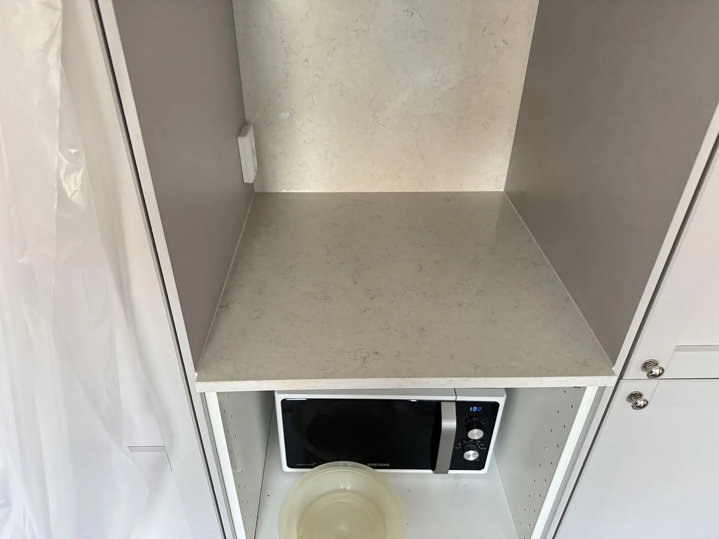 Polerad Silestone Snowy Ibiza som arbetsyta och väggsten i en köksnisch under montering i Karlshamn.