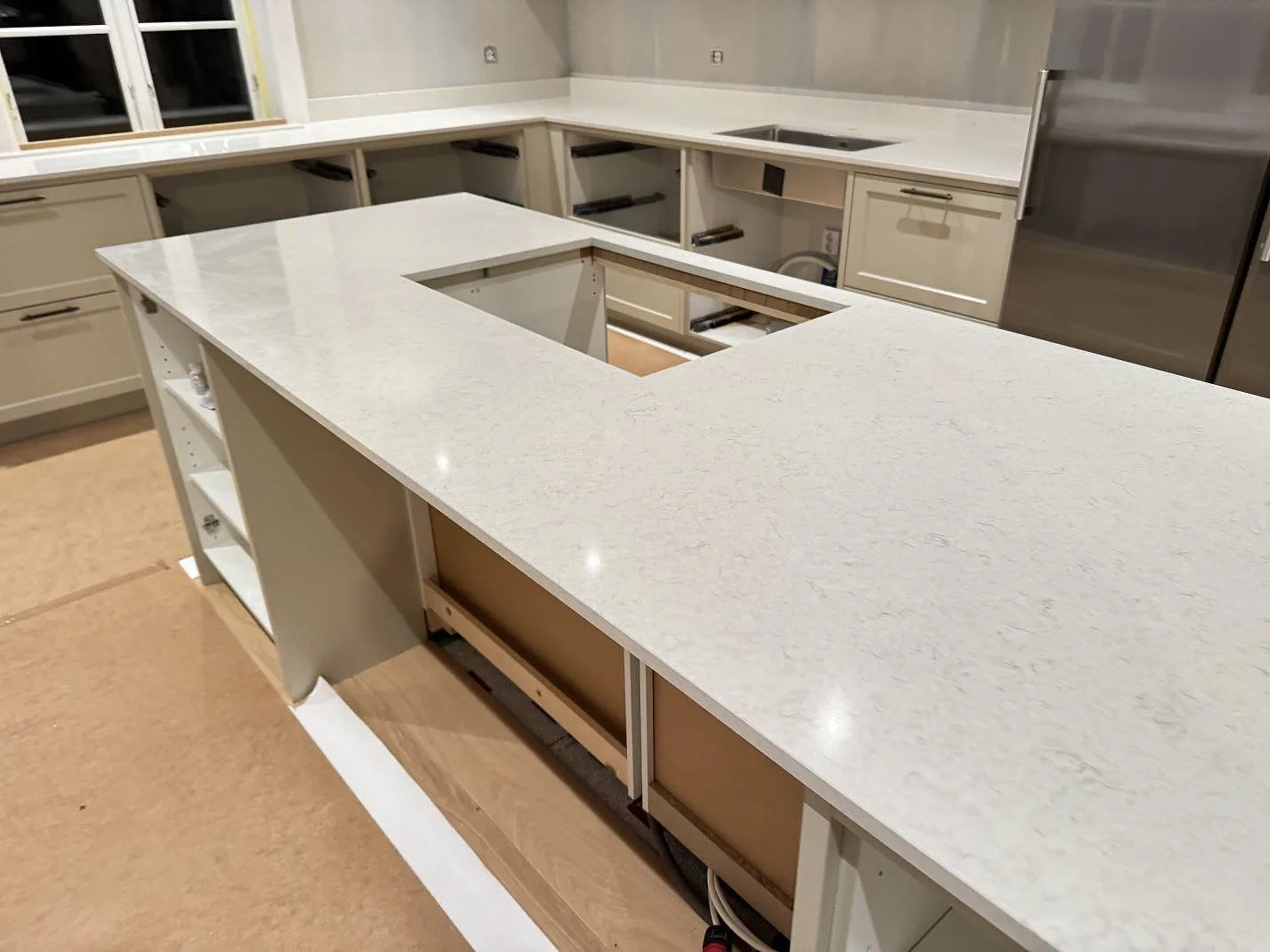 Köksö i vit Silestone Snowy Ibiza med hällurtag, polerad yta och fin grå ådring, med väggrundens diskho i bakgrunden, Karlshamn.