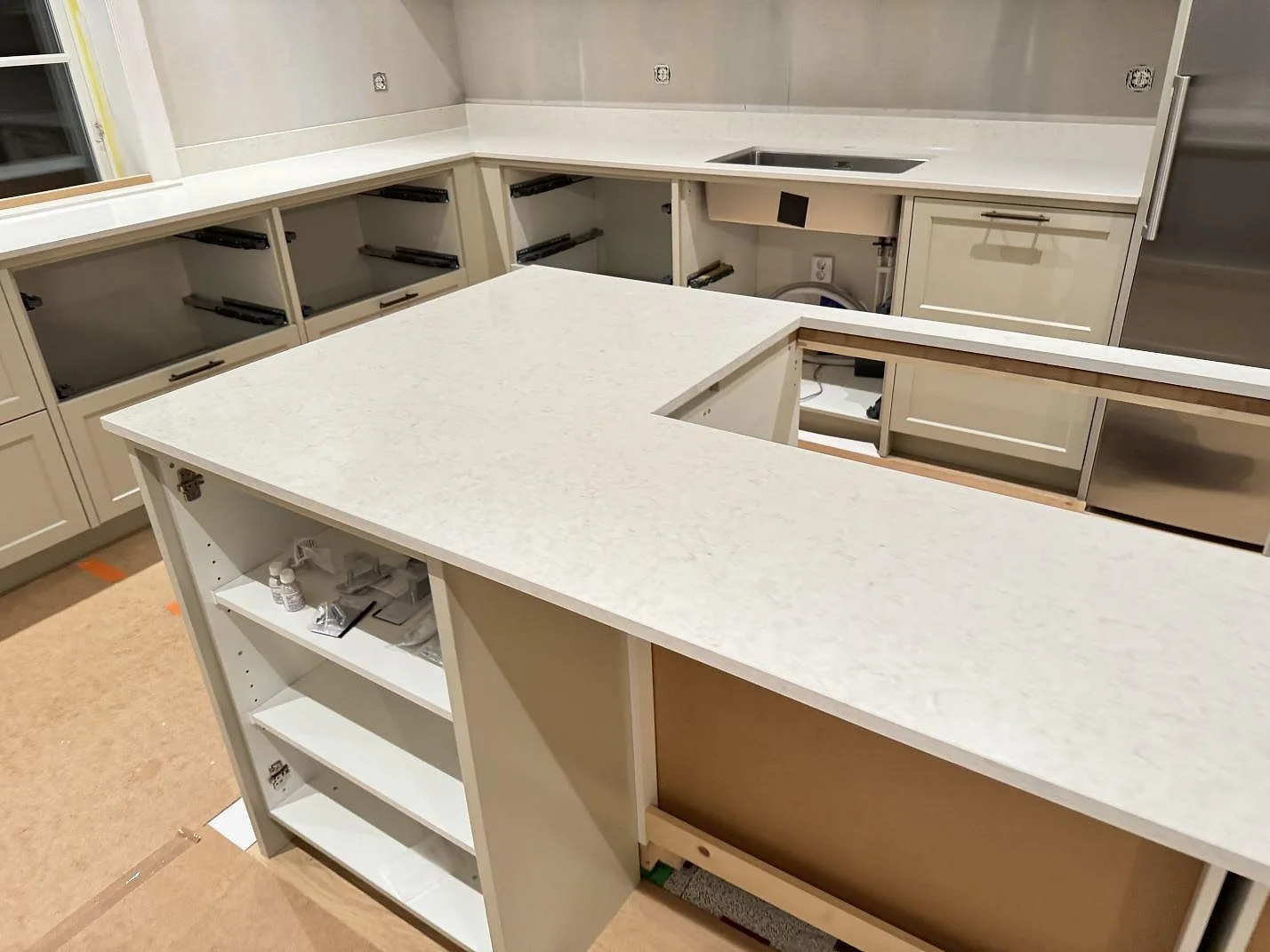 U-format kök i Silestone Snowy Ibiza under montering, med köksö i förgrunden och underlimmad rostfri diskho i väggrunden, Karlshamn.