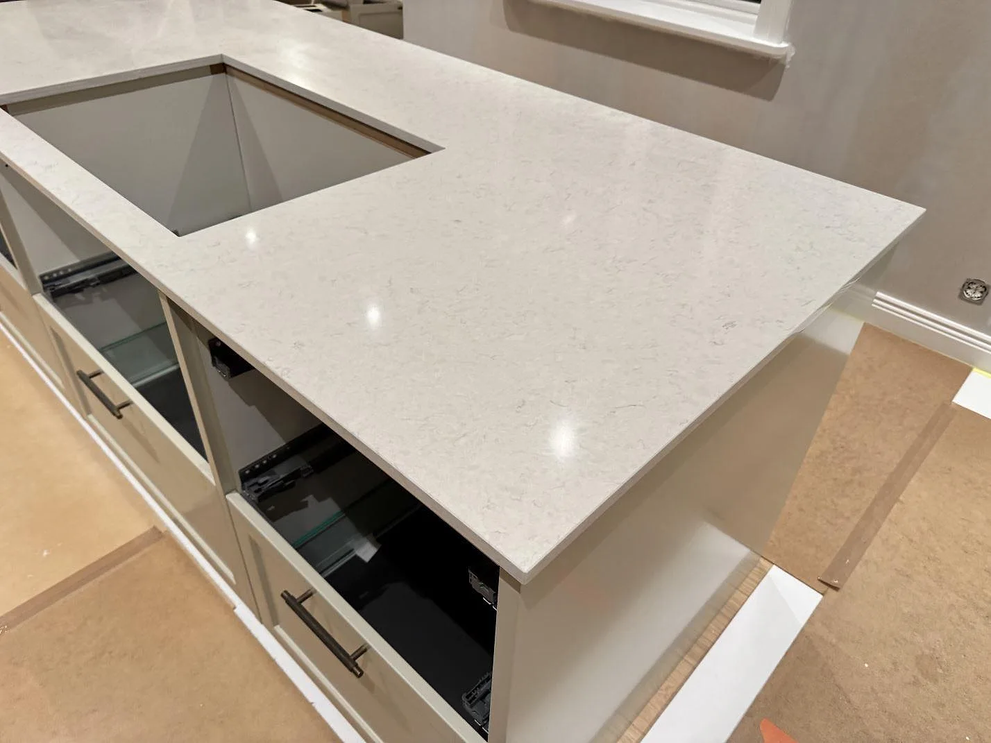Köksbänk i Silestone Snowy Ibiza med underlimmad rostfri diskho och stort hällurtag, polerad yta, under montering i Karlshamn.