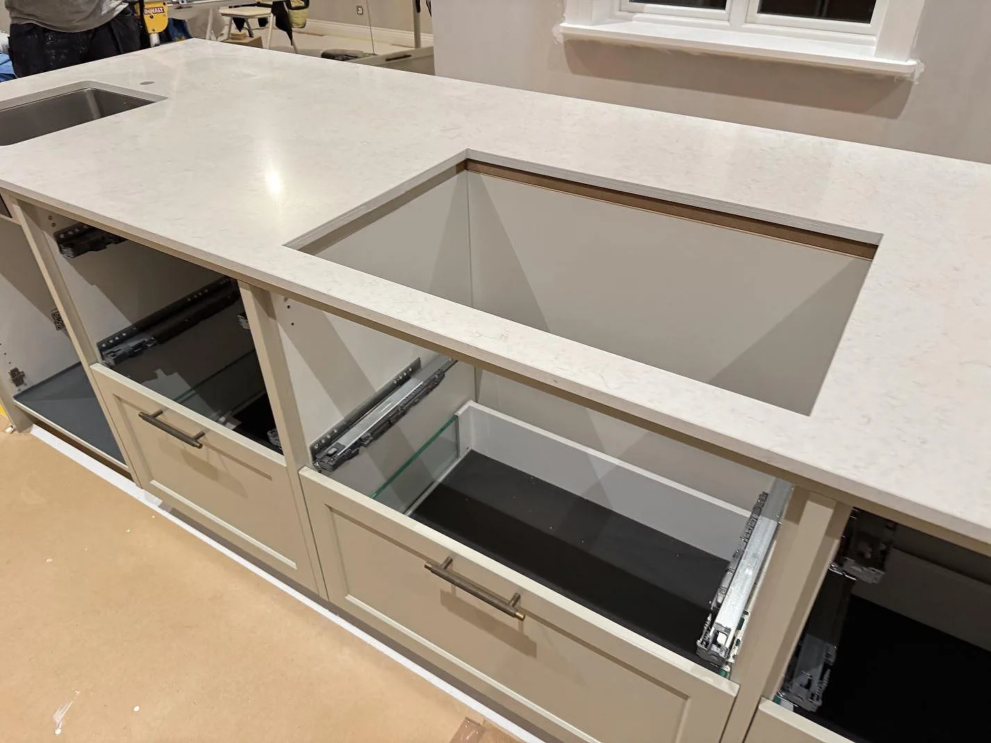 Perimeterbänk i Silestone Snowy Ibiza med underlimmad rostfri diskho och hällplats, polerad komposit i ett kök under montering i Karlshamn.