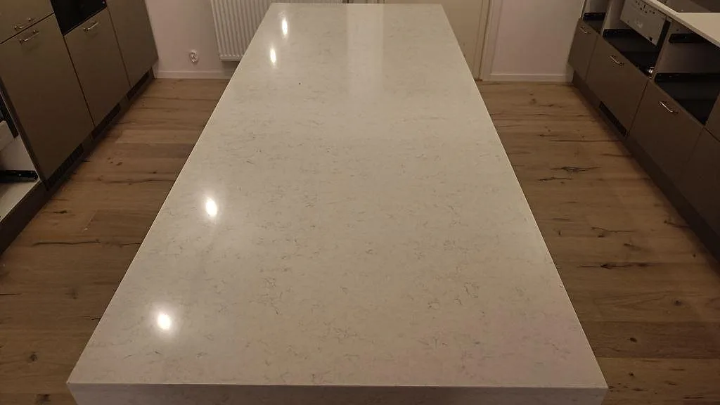Polerad ovansida på köksön i vit Silestone Snowy Ibiza med grå ådring i ett kök i Kivik.