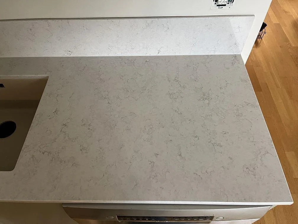 Polerad Silestone Snowy Ibiza köksbänkskiva med diskhoursparning och mjuk grå ådring i Klagshamn.