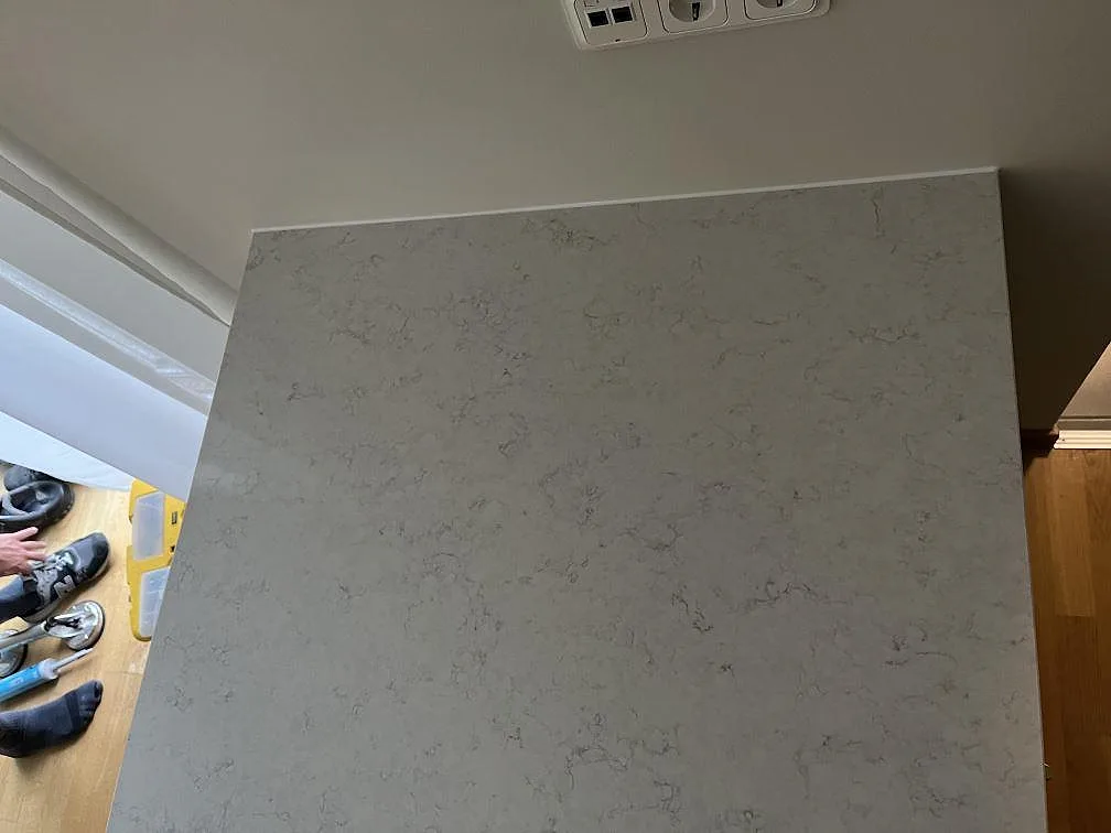 Polerad köksö i vit Silestone Snowy Ibiza med grå ådring, sedd uppifrån, i ett kök i Klagshamn.