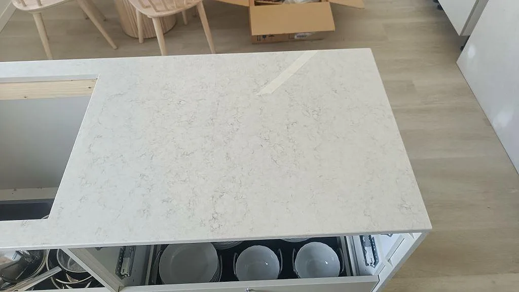 Köksö i vit Silestone Snowy Ibiza med nedfälld sida ner mot golvet, polerad kvartskomposit i Klippan.