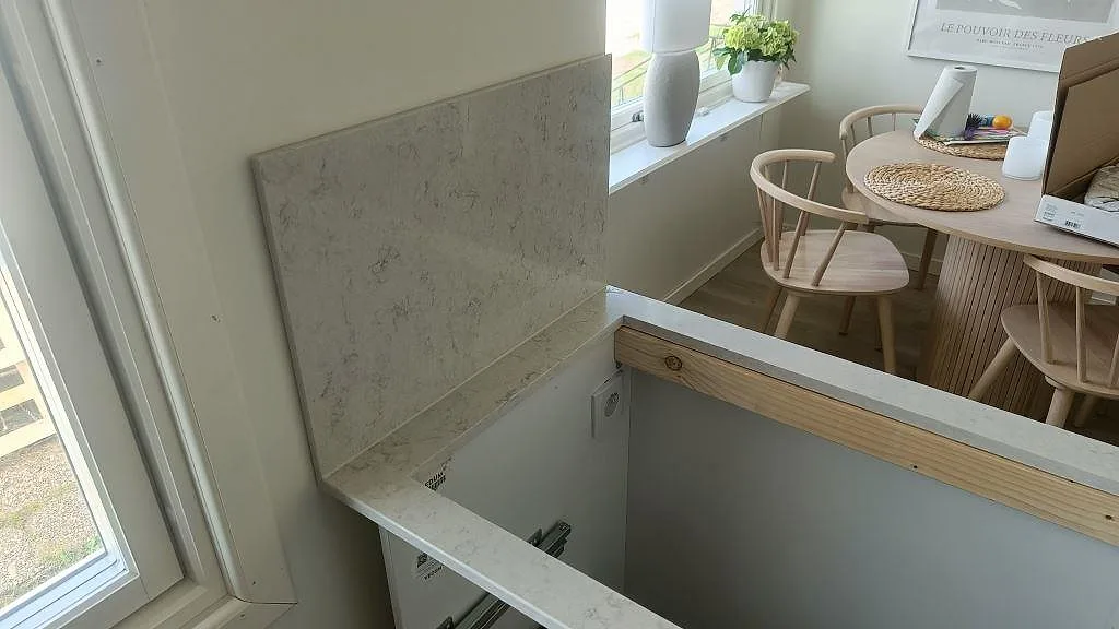 Urtag för häll i installerad köksbänkskiva av Silestone Snowy Ibiza, vit kvartskomposit med mjuk grå ådring, i ett kök i Klippan.