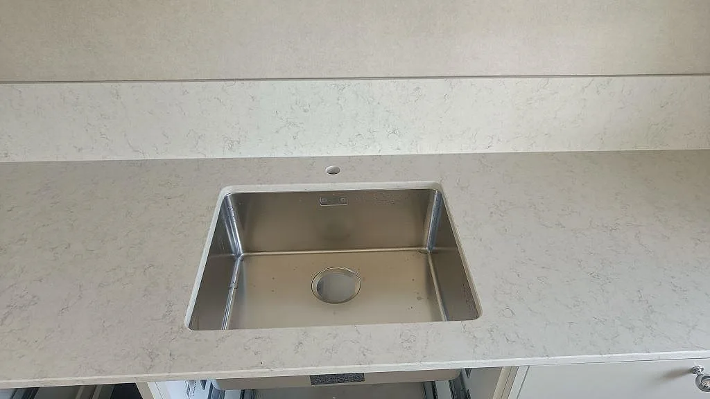 Underlimmad rostfri diskho i polerad Silestone Snowy Ibiza köksbänkskiva med borrat blandarhål i Klippan.