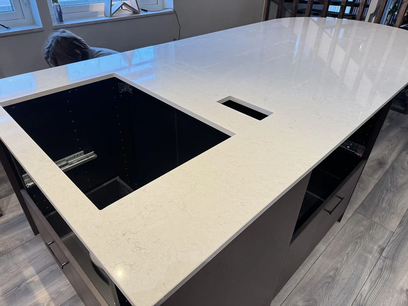 Polerad köksö i Silestone Snowy Ibiza sedd från sidan med stor underlimmad diskho och infälld bänkkontakt i ett kök under montering i Klippan.