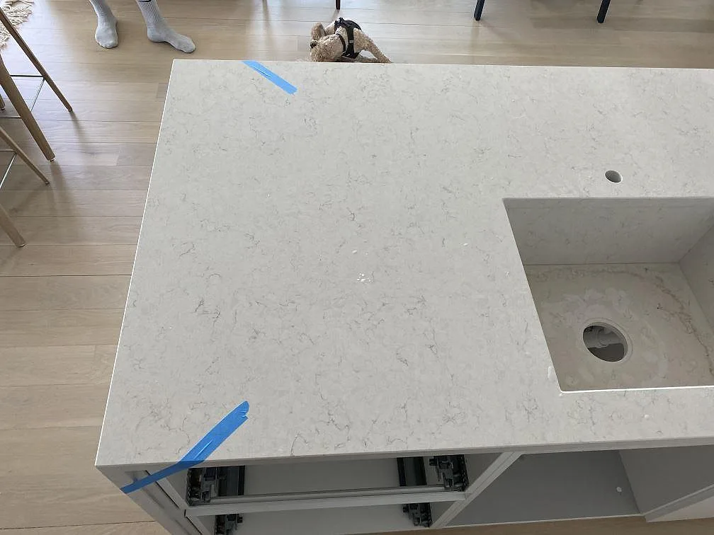 Närbild av polerad Silestone Snowy Ibiza på köksön med diskret grå ådring, kranhål och öppning för ho i ett kök i København V.
