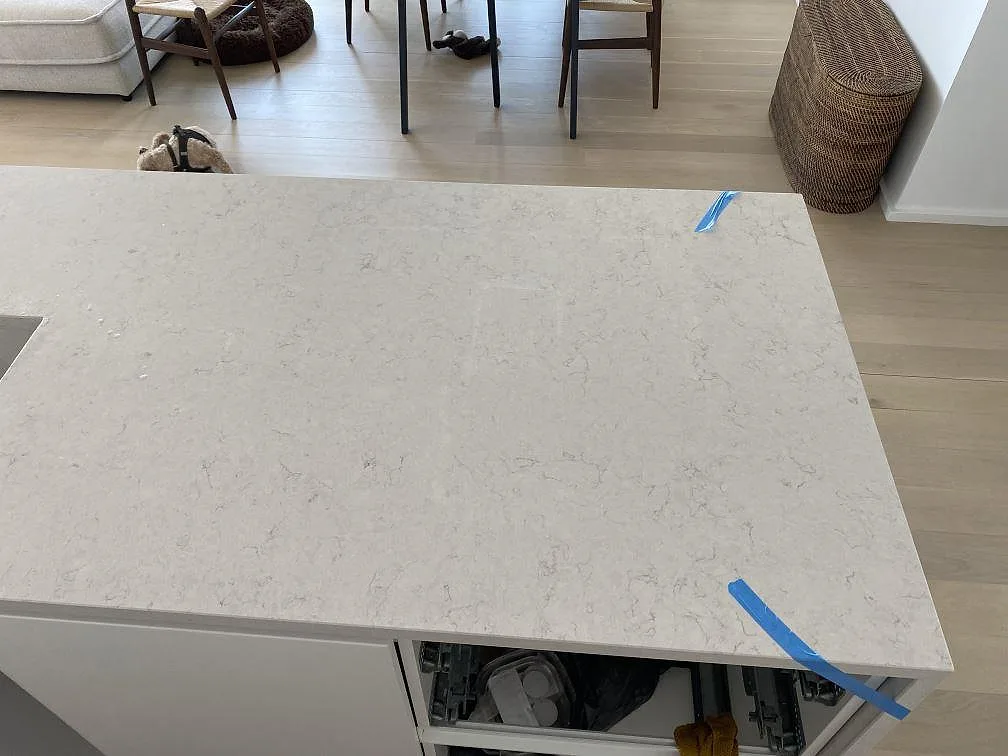 Polerad Silestone Snowy Ibiza på köksön sedd uppifrån, med ljus kvartskomposit och blå monteringstejp i ett kök i København V.
