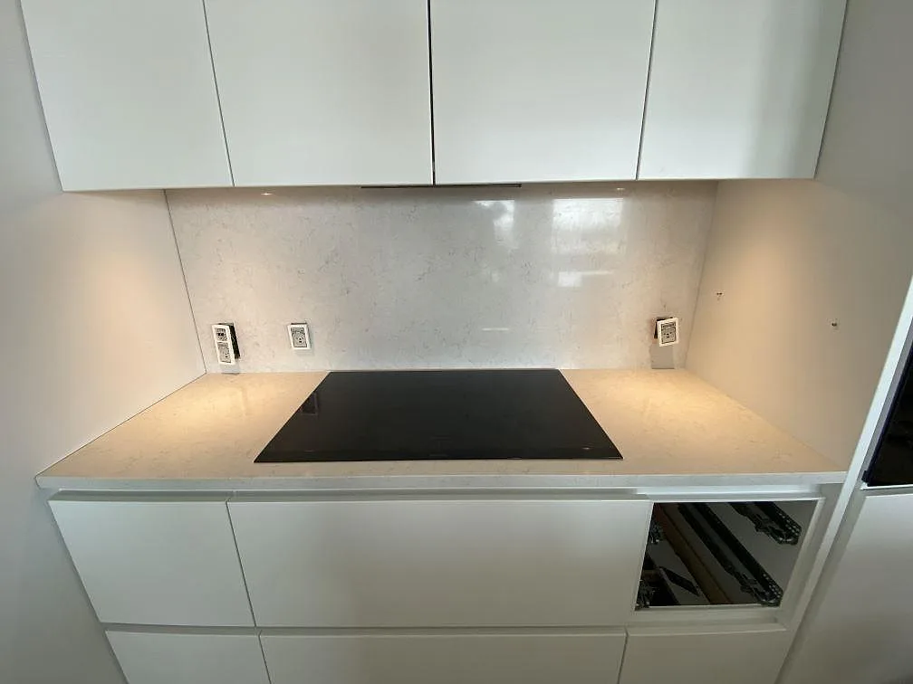 Rak köksbänkskiva i polerad Silestone Snowy Ibiza med infälld häll och matchande stänkskydd upp till överskåpen i ett kök i København V.