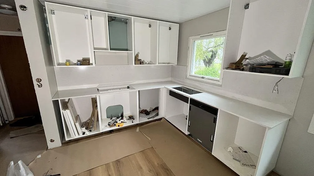 Polerad kompositbänkskiva i Silestone Snowy Ibiza med ljus ådring längs ett kök under montering i Köping.