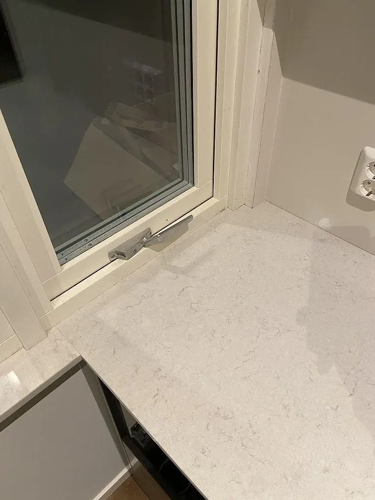 Närbild på den polerade ytan i vit Silestone Snowy Ibiza med mjuk gråmelerad ådring i ett kök i Kullavik.