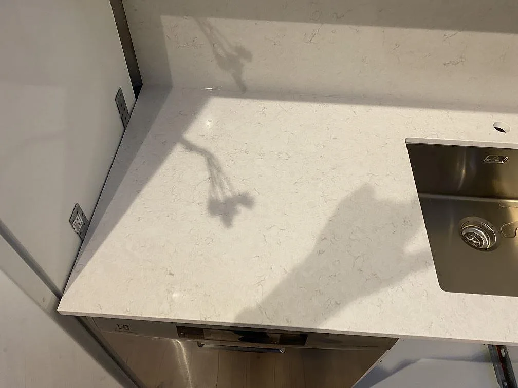 Detalj av vit Silestone Snowy Ibiza-bänkskiva vid diskhozonen, polerad kvartskomposit med grå ådring i Kungsbacka.
