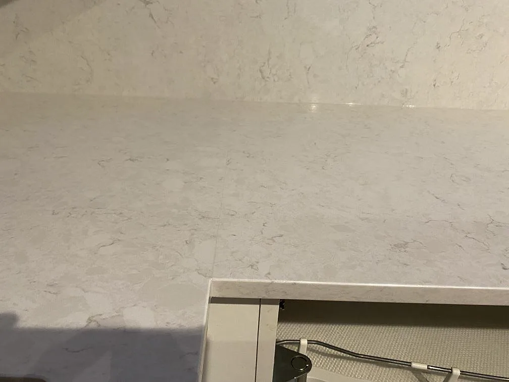 Närbild av polerad Silestone Snowy Ibiza, vit kvartskomposit, med diskret grå ådring och stänkkant i Kungsbacka.