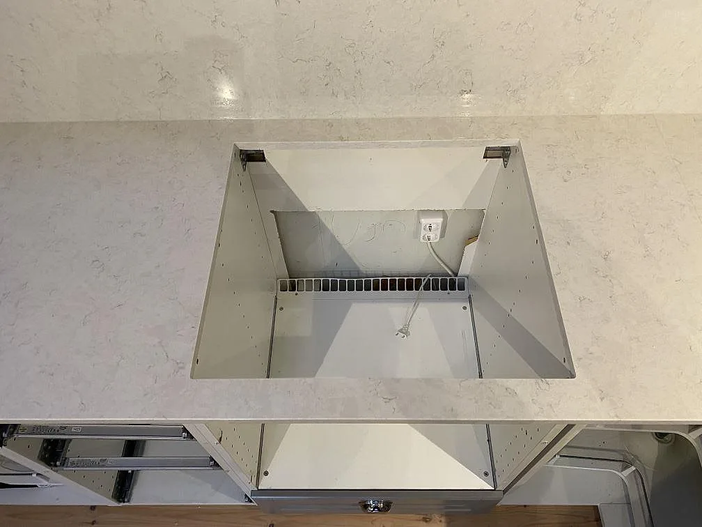 Polerad Silestone Snowy Ibiza som köksbänkskiva med stort urtag i stenen och öppna skåpstommar i Kungsbacka.