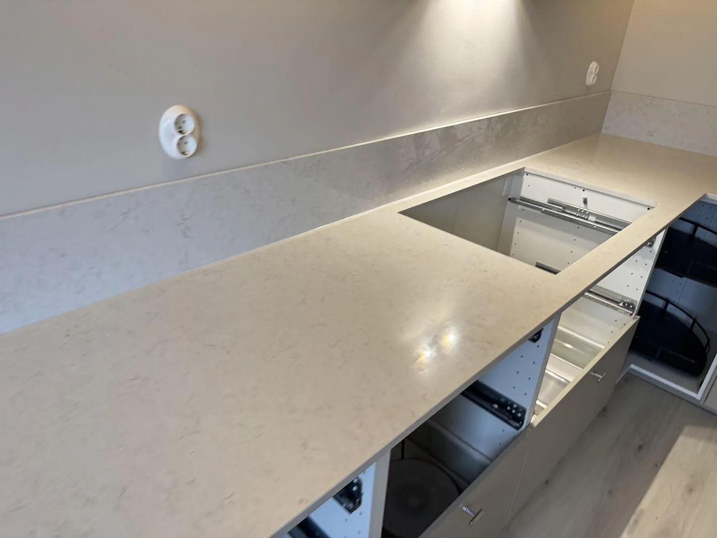 L-format bänkskiva i vit Silestone Snowy Ibiza med returbänk och uppvikt stänkkant i ett kök i Laholm.